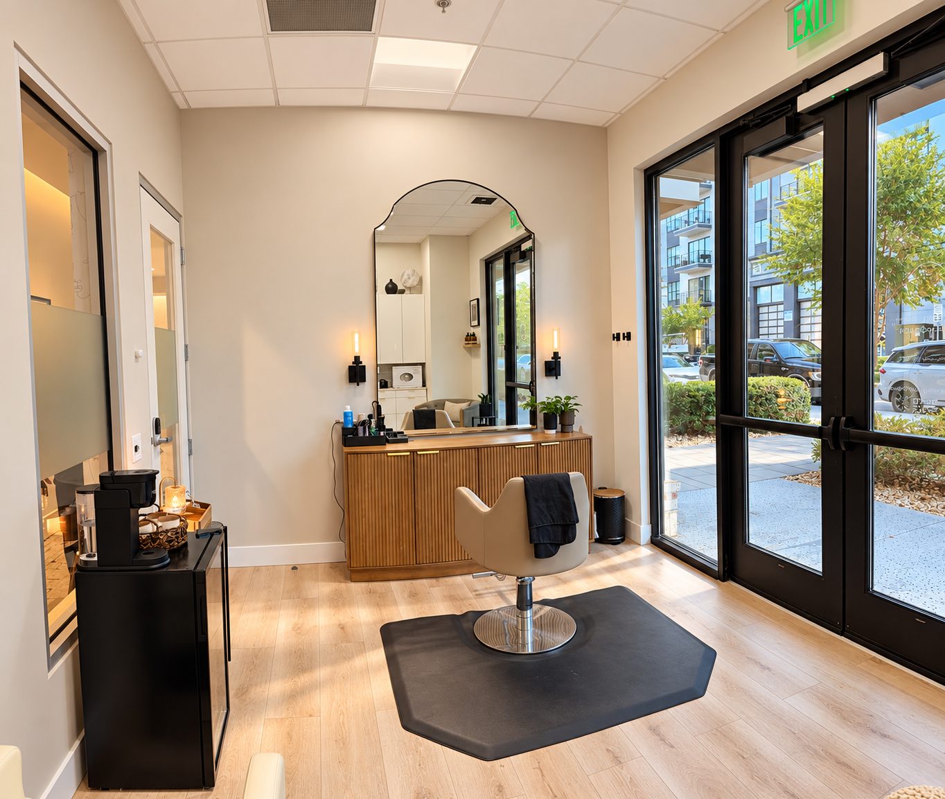 The SK Hair + Beauty studio: a styling chair facing an arched mirror beside tall windows